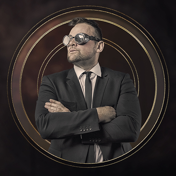 A person in a suit pretending to look steam punk by wearing goggles