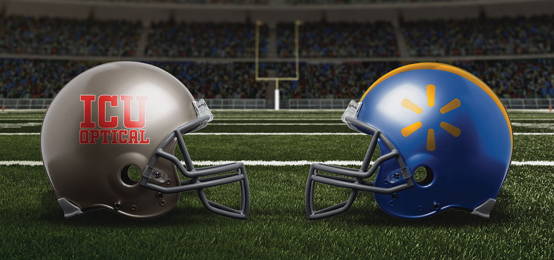 Picture of 2 football helmets. One helment has a collegiate font that says ICU Optical on the side. The other helmet has an abstract shape in yellow on a blue base.