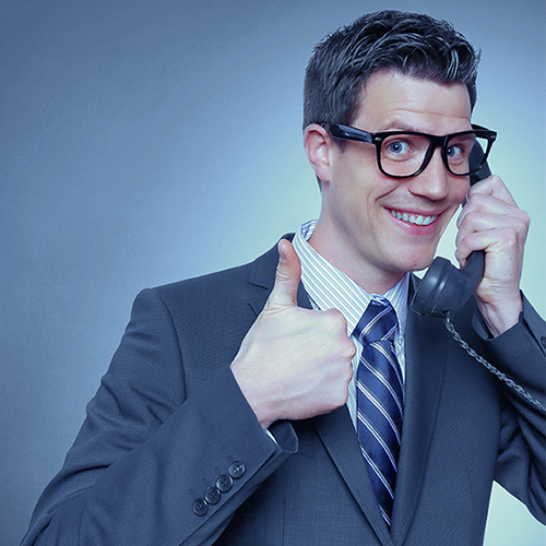 Picture of a business man on the phone with a goofy smile and giving the 'thumbs up' sign