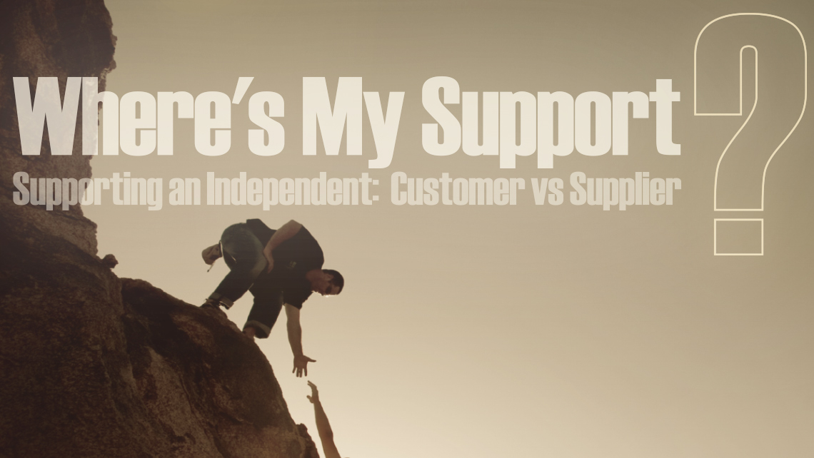 Hero image for article "Where's My Support? Supporting an Independent: Customer vs Supplier". Man reaching down to help another man climb a cliff.