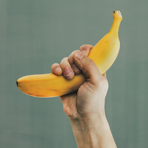 Thumbnail image for article "What is OPT? - The Philosophy of OPT". A hand making a first holding a banana.