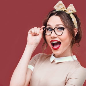 "Woman Adjusting Glasses" image for "It's Just Too Big!" article. Woman adjusting her glasses and smiling at the camera.