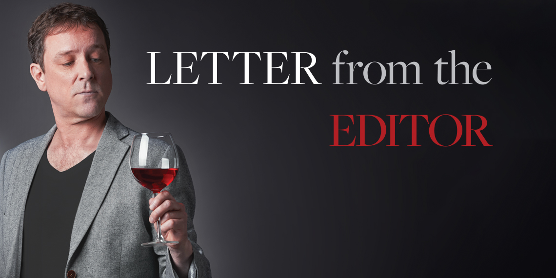 Hero image for "Letter from the Editor" article. Photo of a man holding a glass of red wine.